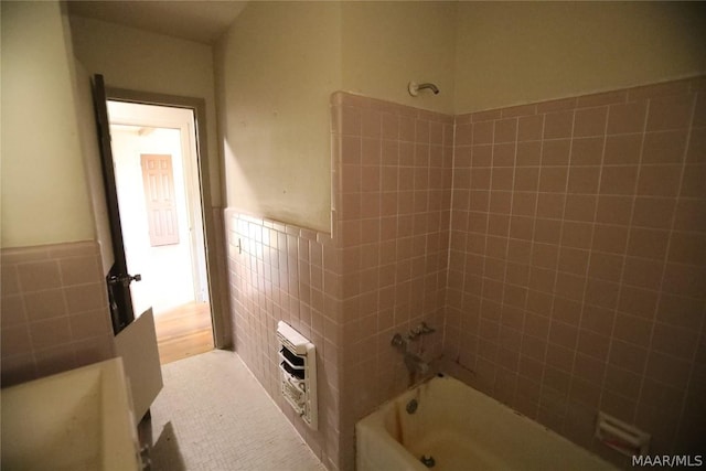 bathroom featuring tile walls, heating unit, and shower / bathtub combination