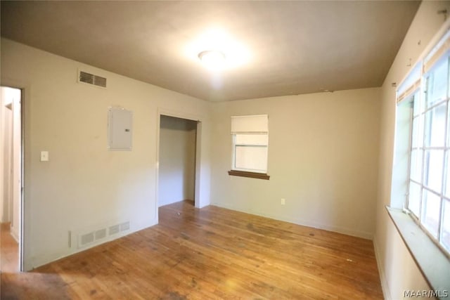 unfurnished room with electric panel and light wood-type flooring