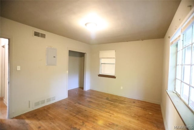 unfurnished room featuring electric panel, light hardwood / wood-style flooring, and a wealth of natural light