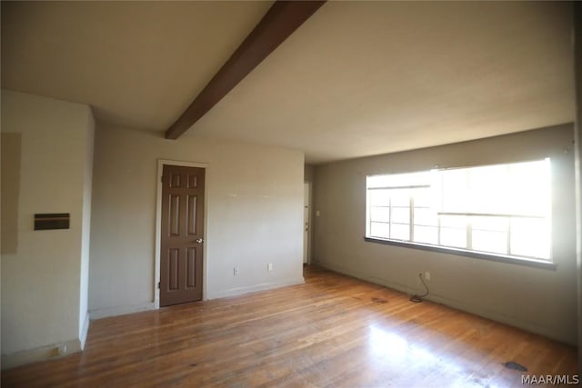 spare room with light wood-type flooring and beamed ceiling