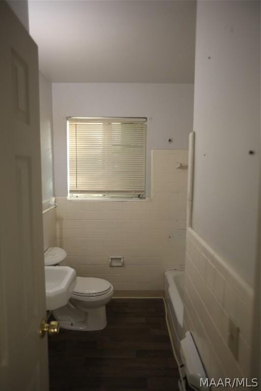 bathroom featuring toilet, wood-type flooring, tile walls, and a bathing tub