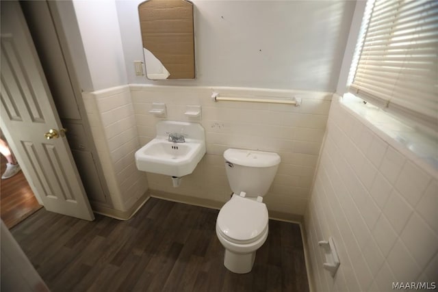 bathroom with toilet, hardwood / wood-style flooring, tile walls, and sink