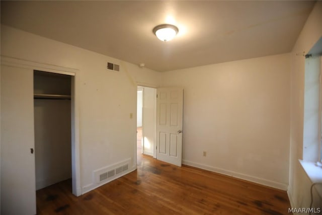 unfurnished bedroom with a closet and dark wood-type flooring