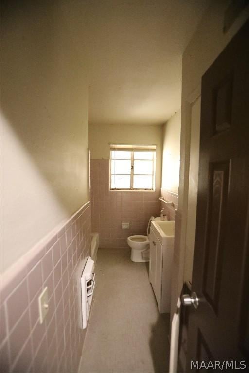 bathroom featuring toilet, vanity, tile walls, and heating unit