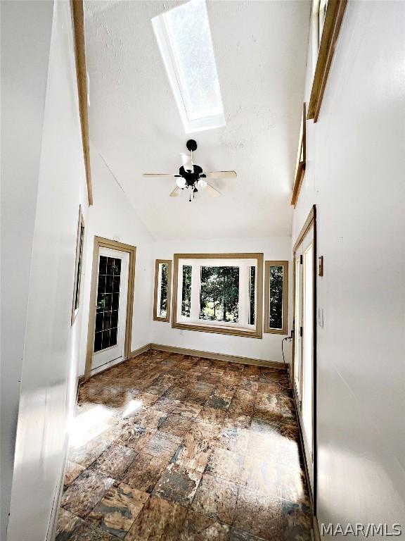 interior space with a wealth of natural light, a skylight, high vaulted ceiling, and ceiling fan