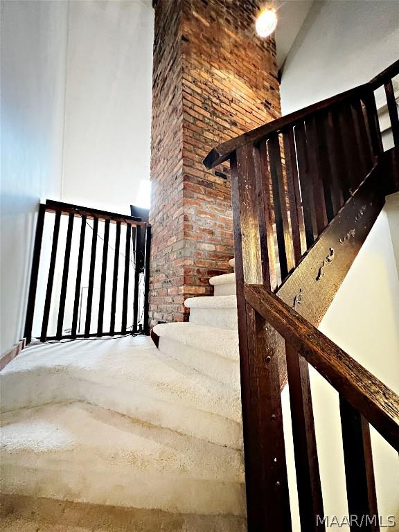 staircase featuring a towering ceiling and brick wall