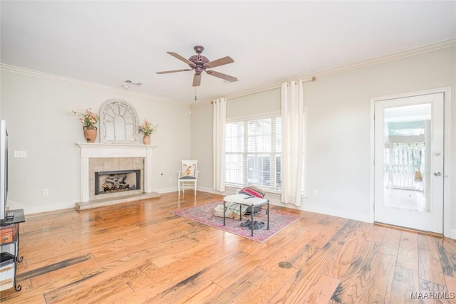 living room with a tile fireplace, crown molding, and hardwood / wood-style flooring