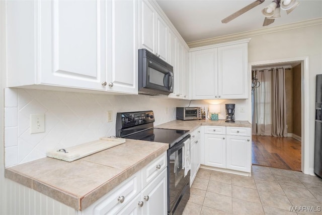 kitchen featuring white cabinets, light tile patterned floors, and black appliances