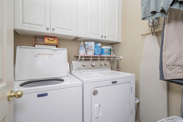 clothes washing area with washer and dryer and cabinets