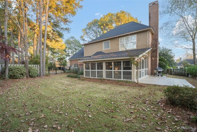 rear view of property with a sunroom, a yard, and a patio