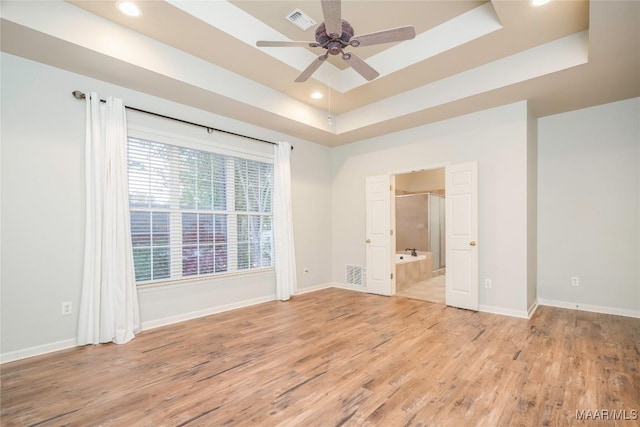 spare room featuring ceiling fan, light hardwood / wood-style floors, and a tray ceiling