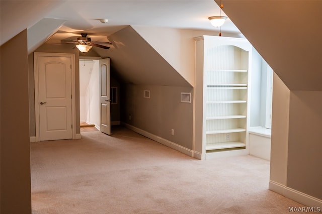 additional living space featuring ceiling fan, built in features, light colored carpet, and lofted ceiling