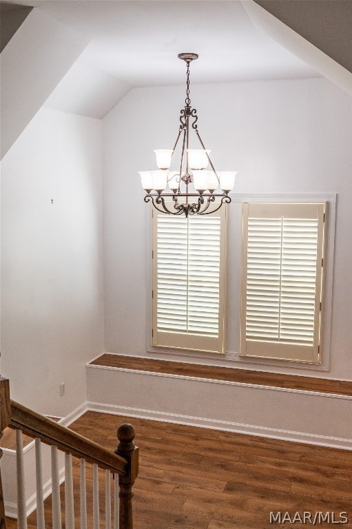 interior space featuring a notable chandelier, wood-type flooring, and vaulted ceiling