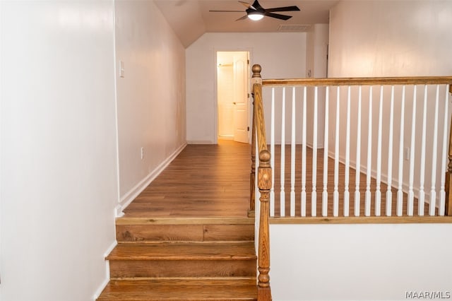 stairs featuring ceiling fan, hardwood / wood-style floors, and vaulted ceiling