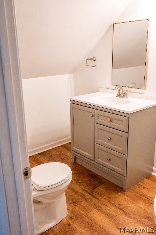 bathroom featuring hardwood / wood-style floors, vanity, toilet, and lofted ceiling