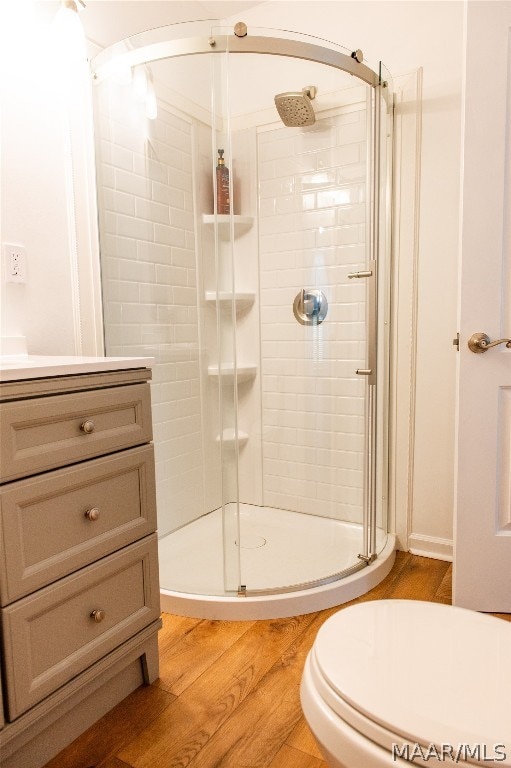 bathroom with hardwood / wood-style flooring, vanity, toilet, and walk in shower