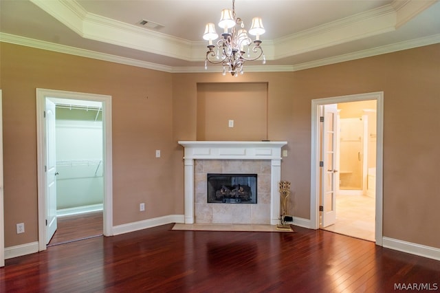 unfurnished living room with a chandelier, a raised ceiling, ornamental molding, and a tiled fireplace