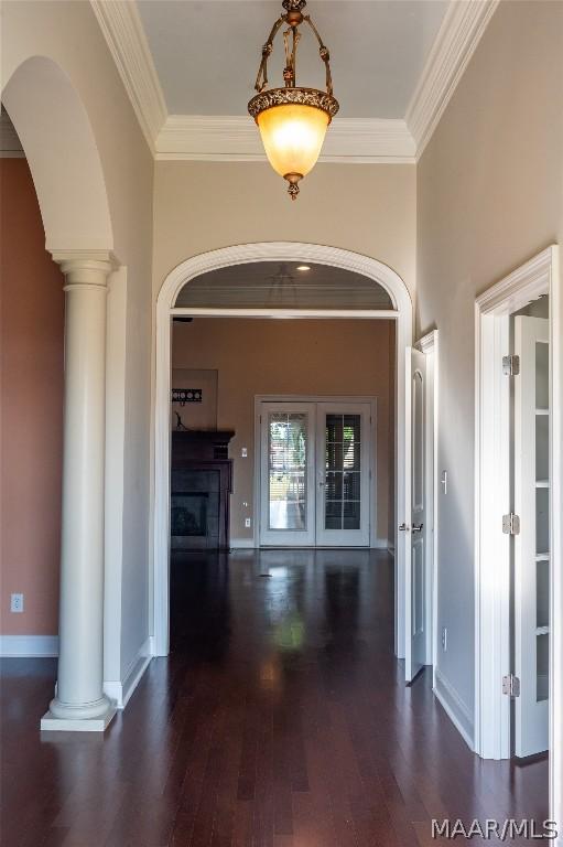 hall with decorative columns, crown molding, and dark hardwood / wood-style flooring