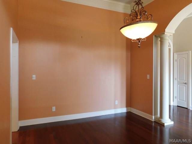 empty room featuring dark hardwood / wood-style flooring, decorative columns, and crown molding