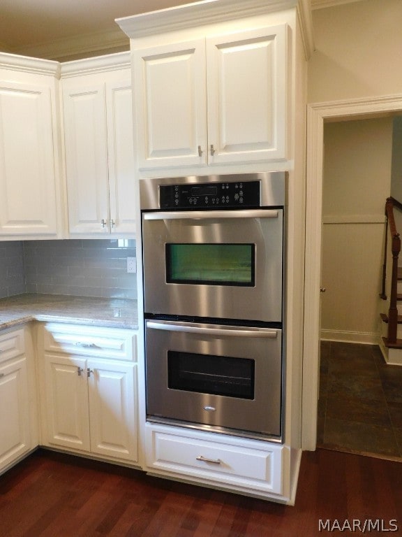 kitchen featuring light stone countertops, dark hardwood / wood-style floors, double oven, backsplash, and white cabinets