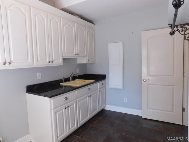 kitchen featuring white cabinetry, sink, and dark tile patterned flooring