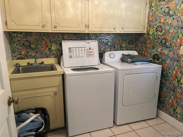 laundry area with cabinets, light tile patterned floors, washer and dryer, and sink