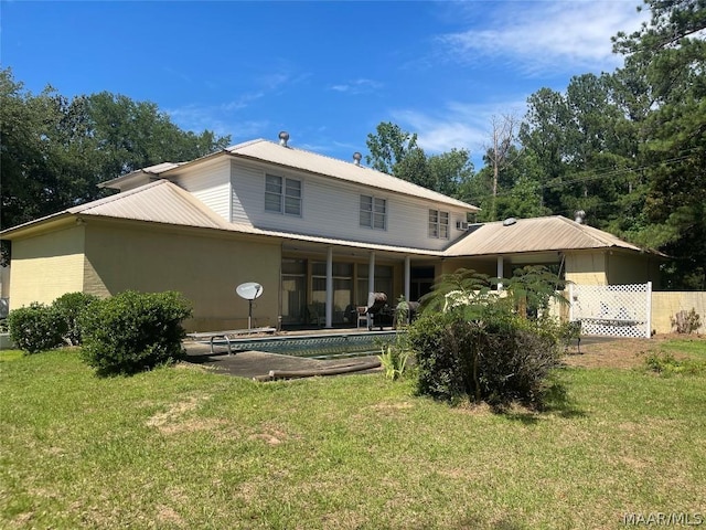 rear view of property featuring a yard, a sunroom, and a swimming pool