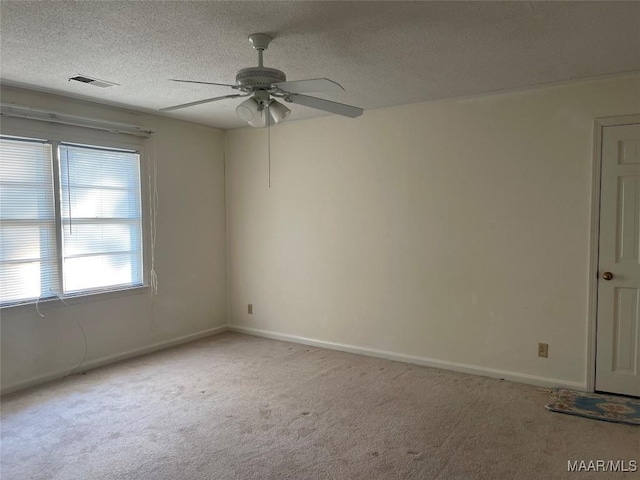 empty room with ceiling fan, light colored carpet, and a textured ceiling