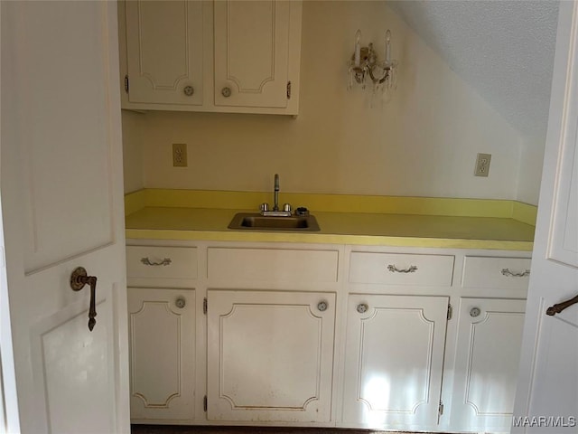 kitchen featuring sink, white cabinets, and a textured ceiling