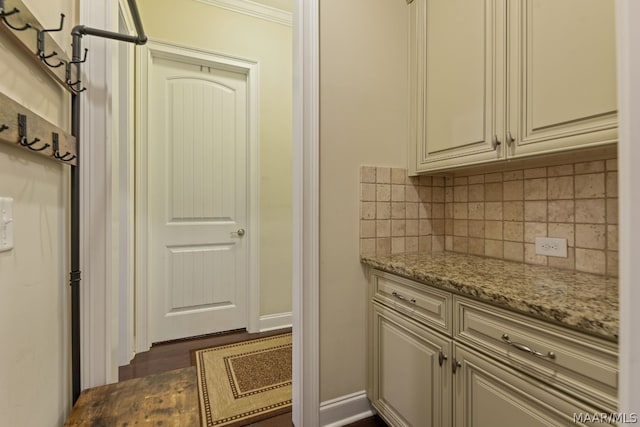 interior space with light stone countertops, tasteful backsplash, dark wood-type flooring, and crown molding