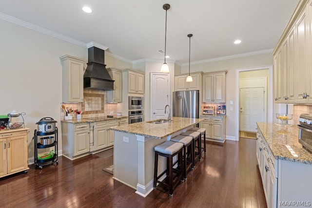 kitchen featuring sink, light stone countertops, an island with sink, custom range hood, and stainless steel appliances