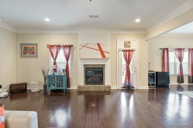 unfurnished living room with hardwood / wood-style floors, ornamental molding, and a tiled fireplace