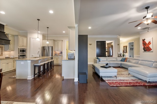 living room with sink, ceiling fan, crown molding, and dark wood-type flooring