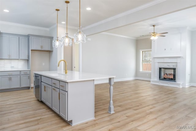 kitchen with light countertops, open floor plan, a kitchen island with sink, a sink, and dishwasher