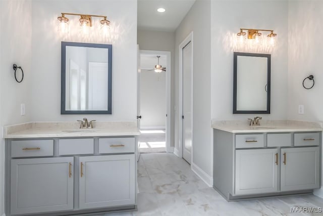 full bathroom with marble finish floor, two vanities, a sink, and baseboards