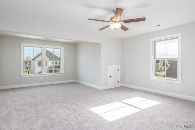 spare room featuring light carpet, ceiling fan, and baseboards