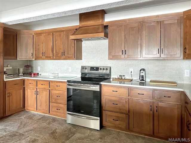 kitchen featuring decorative backsplash, premium range hood, and stainless steel range with electric stovetop