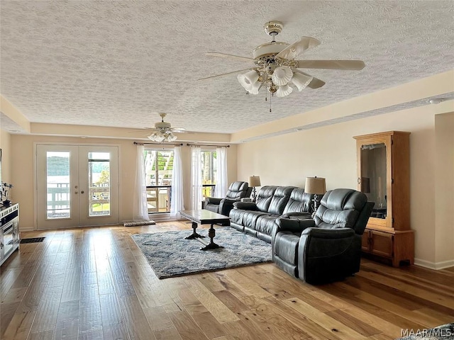 living room featuring ceiling fan, wood-type flooring, and french doors