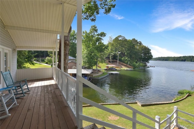 wooden deck with a water view and a lawn