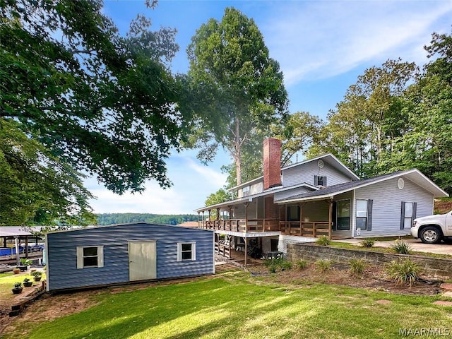 back of property with a yard and an outdoor structure