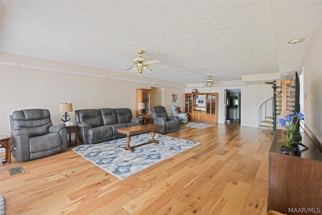 living room featuring hardwood / wood-style floors, a textured ceiling, and ceiling fan