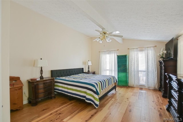 bedroom with vaulted ceiling, ceiling fan, light hardwood / wood-style flooring, and a textured ceiling