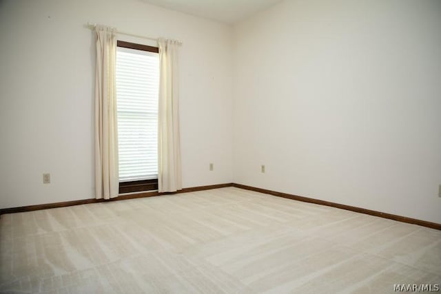 unfurnished room with a healthy amount of sunlight, light colored carpet, and baseboards