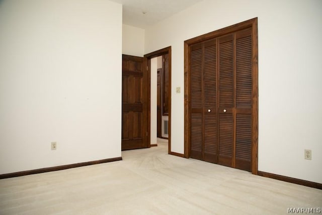 unfurnished bedroom featuring light carpet, a closet, and baseboards