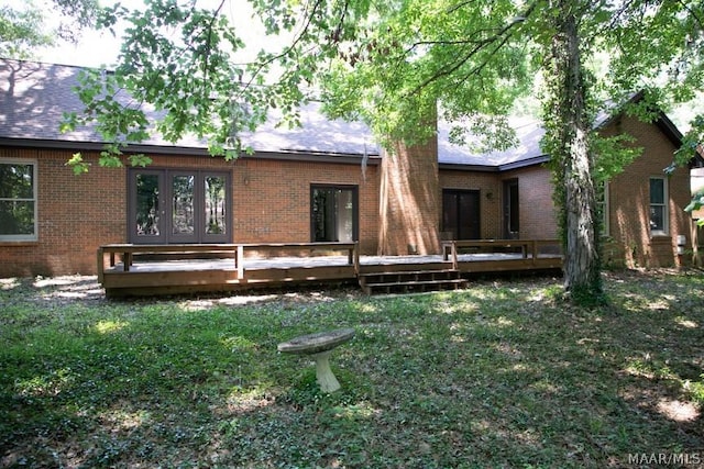 back of house featuring french doors, a wooden deck, and brick siding