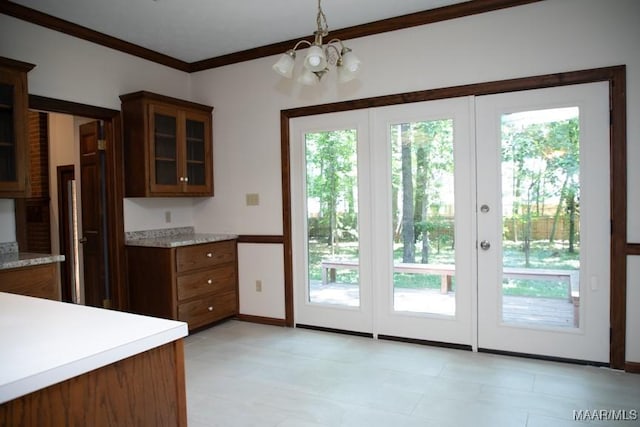 kitchen with light countertops, ornamental molding, glass insert cabinets, and a healthy amount of sunlight