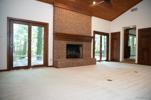 unfurnished living room featuring ceiling fan, a brick fireplace, a towering ceiling, light colored carpet, and wood ceiling