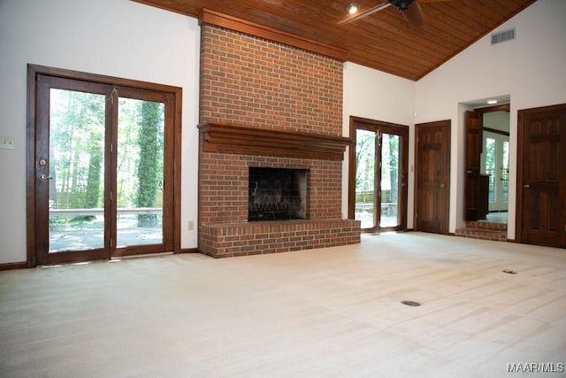 unfurnished living room with a wealth of natural light, wood ceiling, visible vents, and a brick fireplace