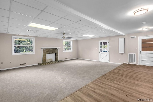 basement with a drop ceiling, hardwood / wood-style floors, a fireplace, and ceiling fan