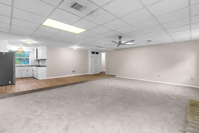 unfurnished living room featuring carpet, a paneled ceiling, and ceiling fan